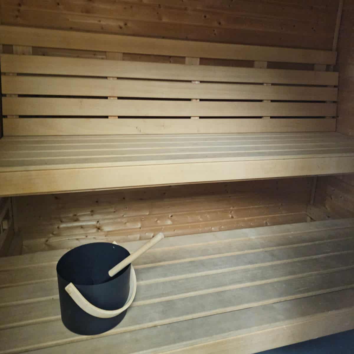wooden sauna benches with a bucket with a ladle on the lower bench