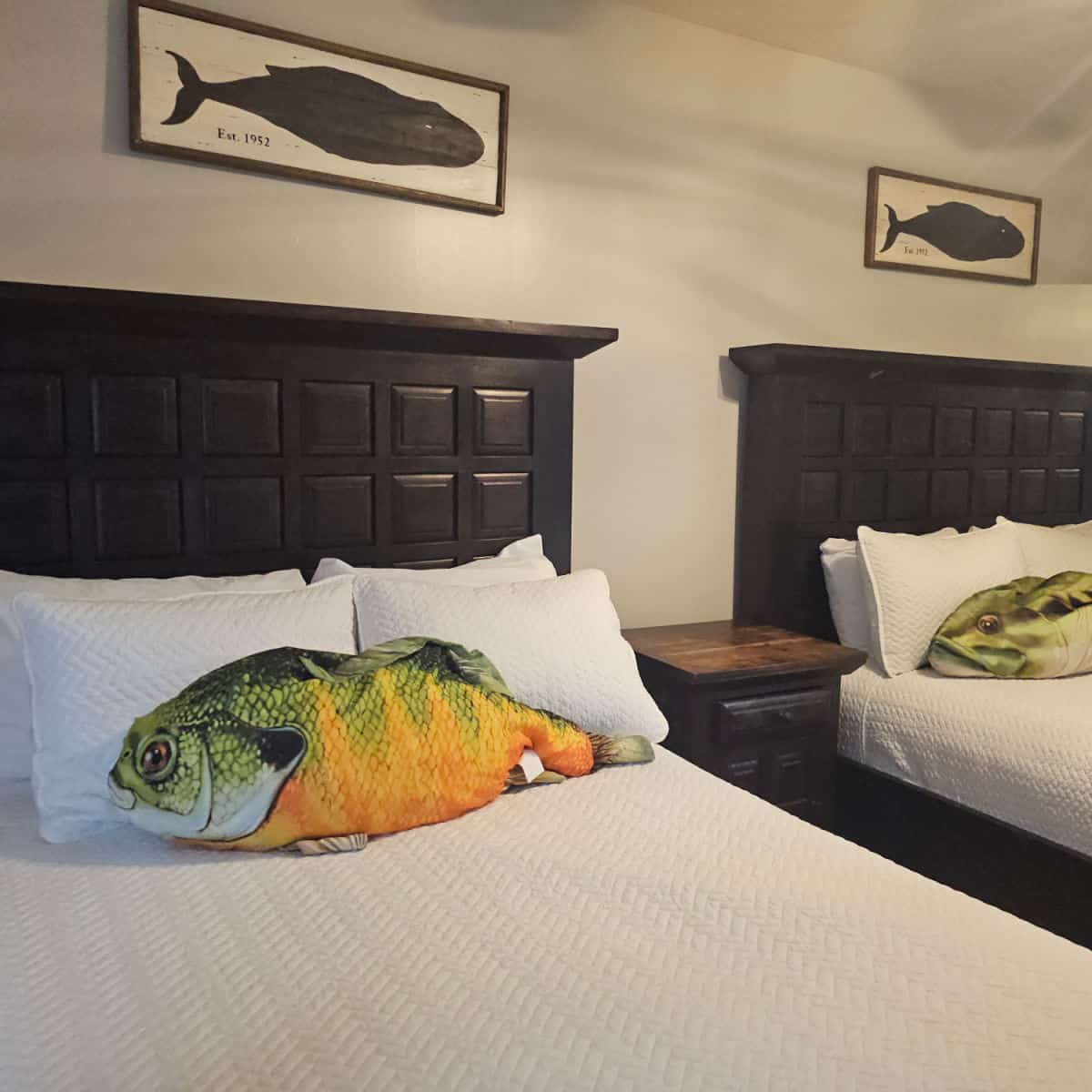 bedroom with two beds, large fish pillows on the beds, fish art over the bed
