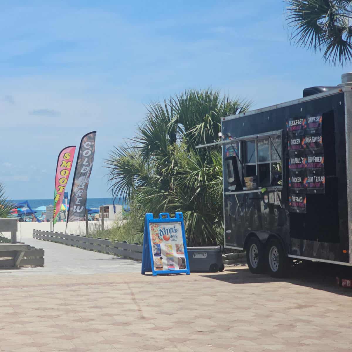food trucks with dippin dots, next to a boadwalk to the beach
