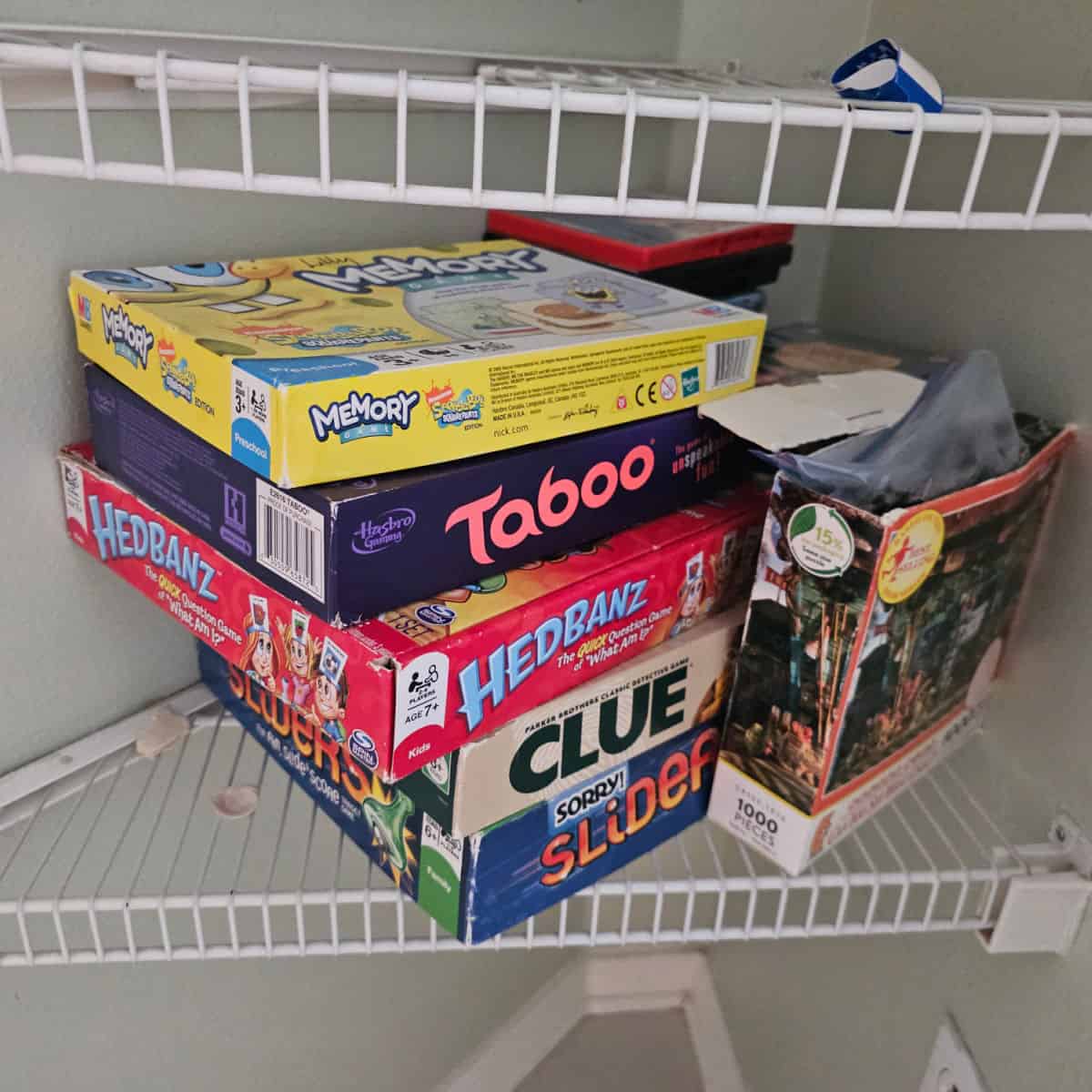 stack of games on a wire closet shelf