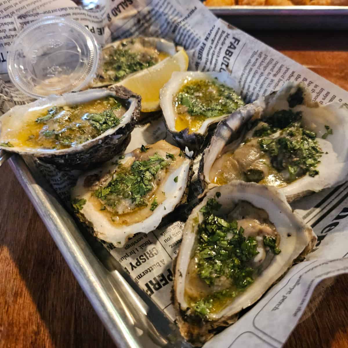 raw oysters in a paper lined tray on a table