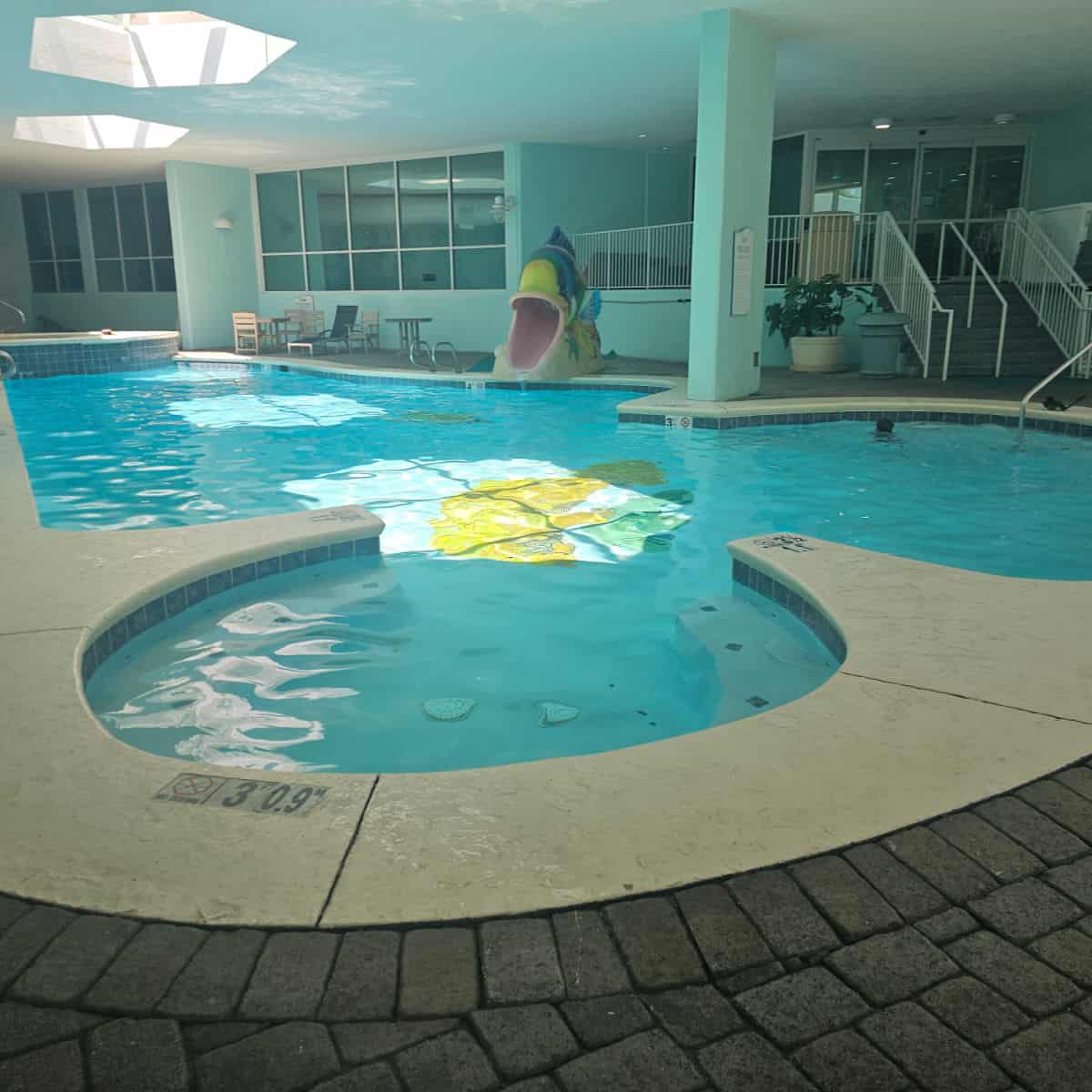indoor pool with fish slide and stairs leading to a door