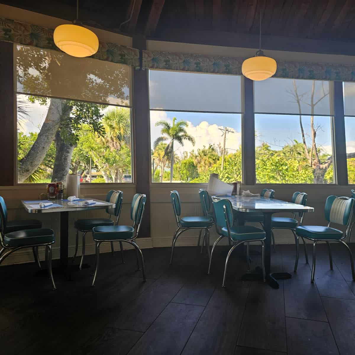 retro chairs next to tables by the window with palm trees outside