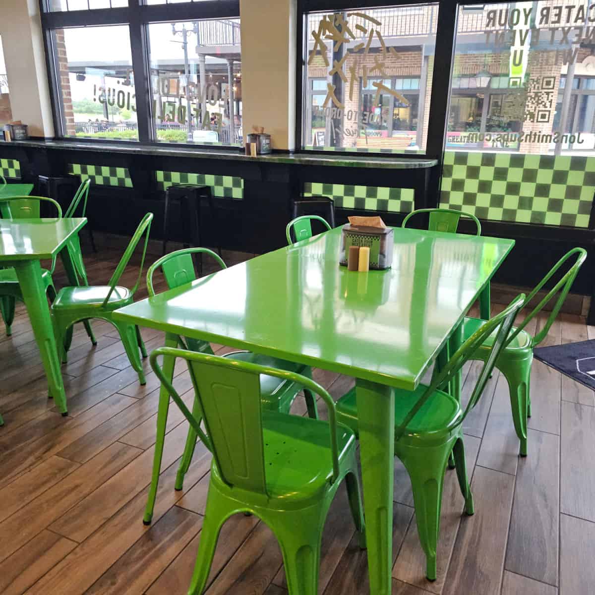 Indoor seating with lime green tables and chairs, windows looking out to another building