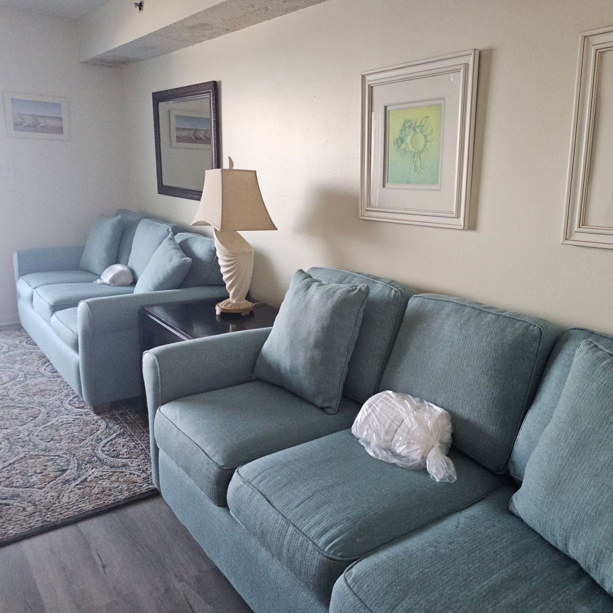 Two blue couches with a table between them and an artistic lap, art on the walls