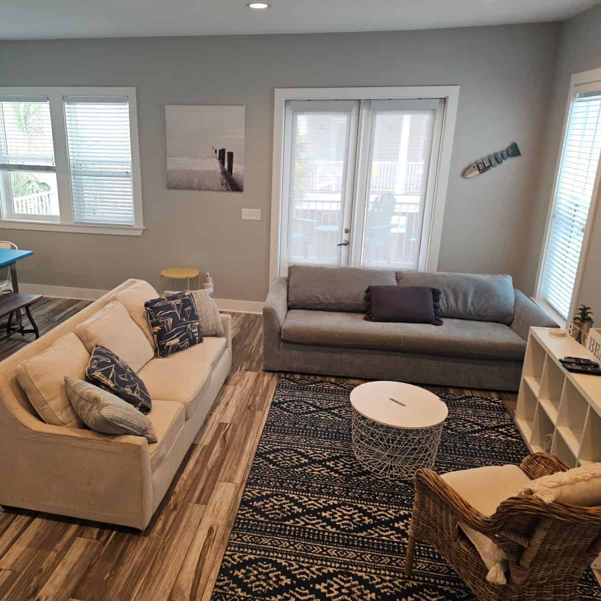 living room area with two couches, a small round table, bookshelf and doors to the deck