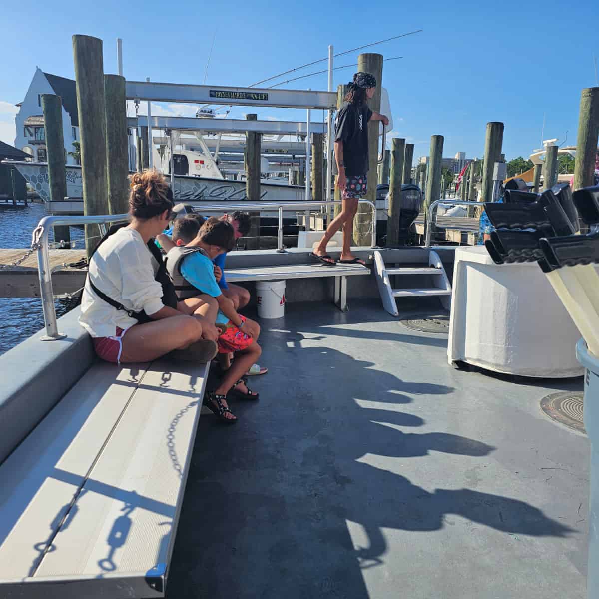 back of a boat with two steps leading down to it, bench along the side with people sitting