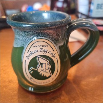 Another Broken Egg Cafe green mug with logo on the front