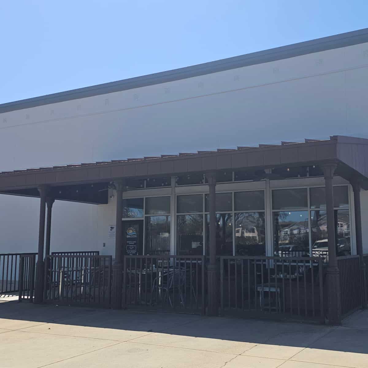 Covered outdoor seating area with tables and chairs, windows to Cafe Destin