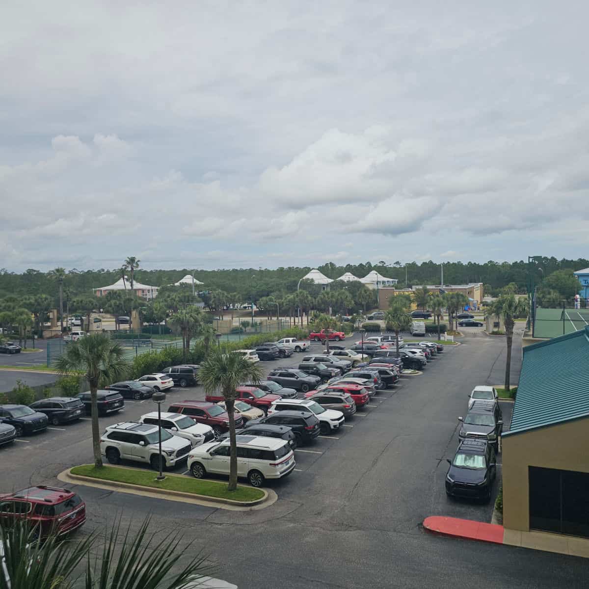 parking lot filled with cars, buildings in the background,
