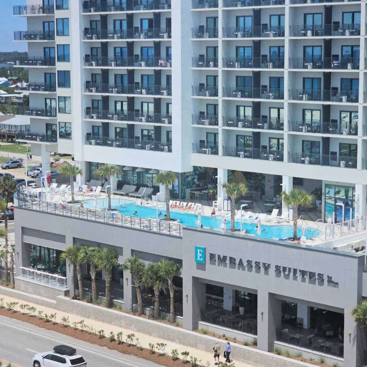 Looking across the street to a pool deck and the Embassy Suites by Hilton sign on the hotel
