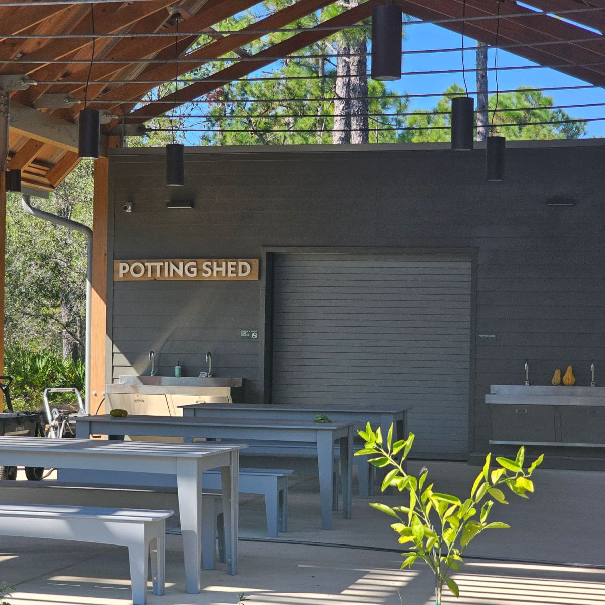 Potting Shed sign on a dark building with tables and benches in front of it