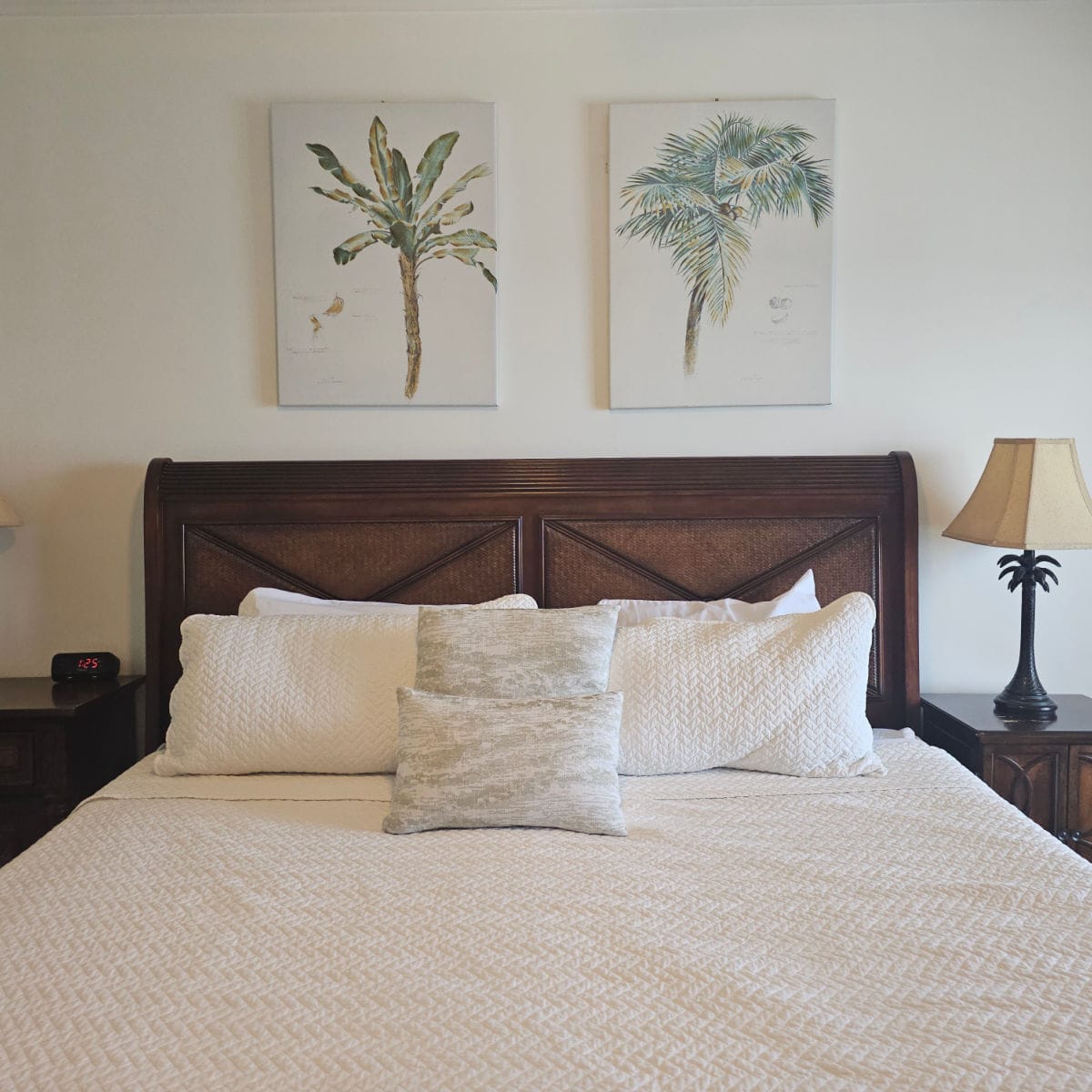 bed with pillows and white cover, palm trees photos on the wall
