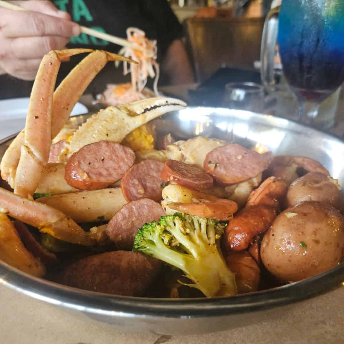 seafood boil in a silver platter with crab, conecuh sausage, potatoes, and corn