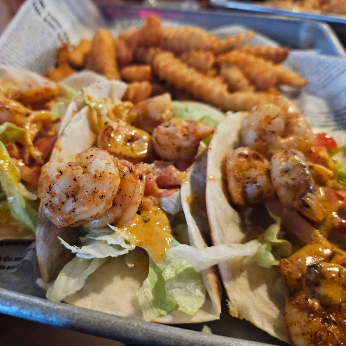 metal tray with shirmp tacos and french fries