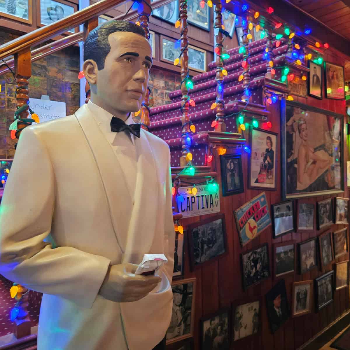 Statue of a man next to a staircase with Christmas lights, wall covered in historic photos