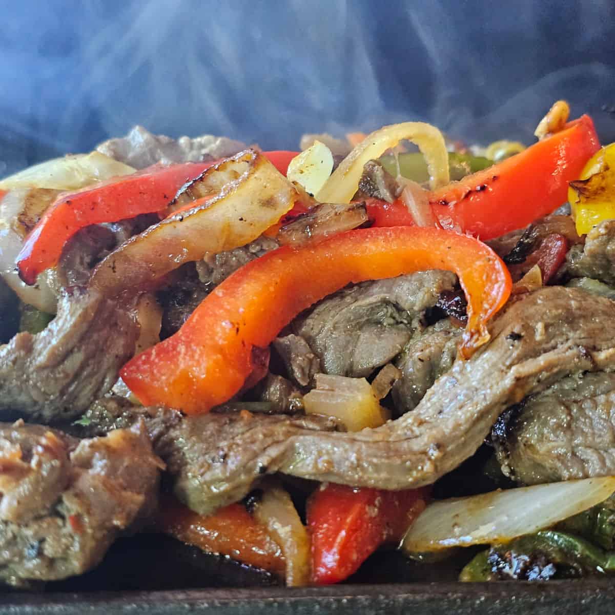 Steak fajita mix with peppers and onions steaming on a platter