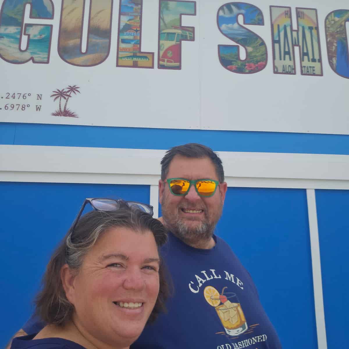 Tammilee and John next to a blue building with Gulf Sho above them