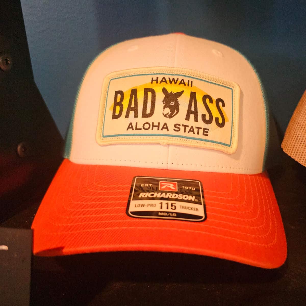 Trucker hat with red brim and a patch with a donkey and Hawaii Bad Ass Aloha state