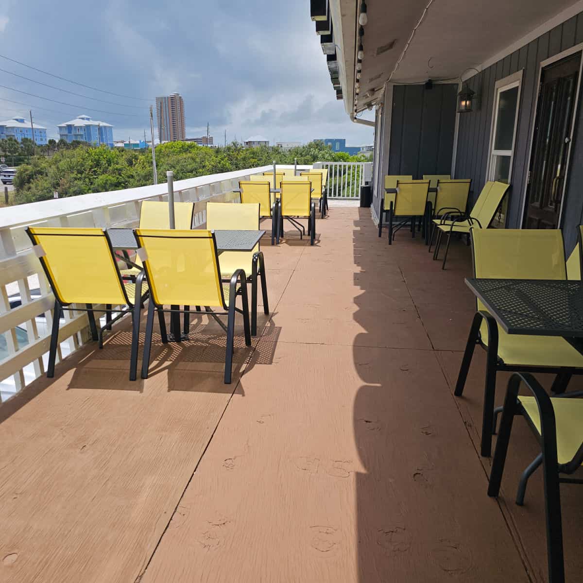 outdoor seating with tables and yellow chairs, condo buildings in the background