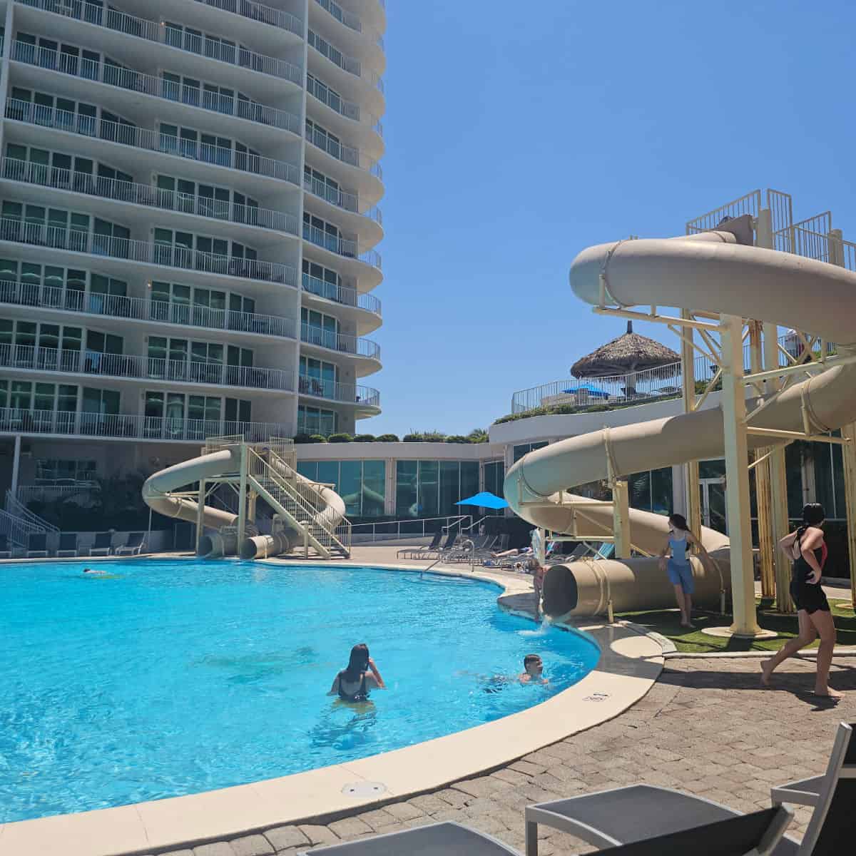 waterslides on both sides of a pool, tall condo building to the left