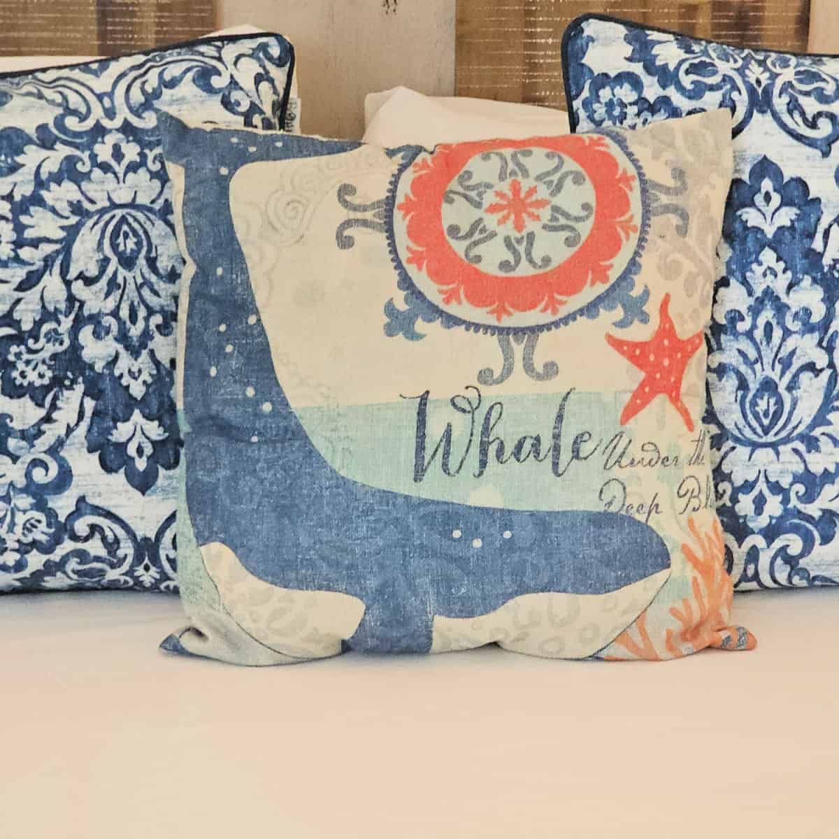 Whale pillow with blue and white pillows on a bed