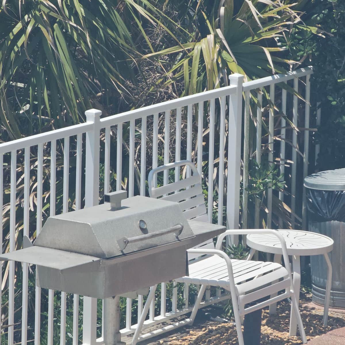 bbq with white chairs and table next to it