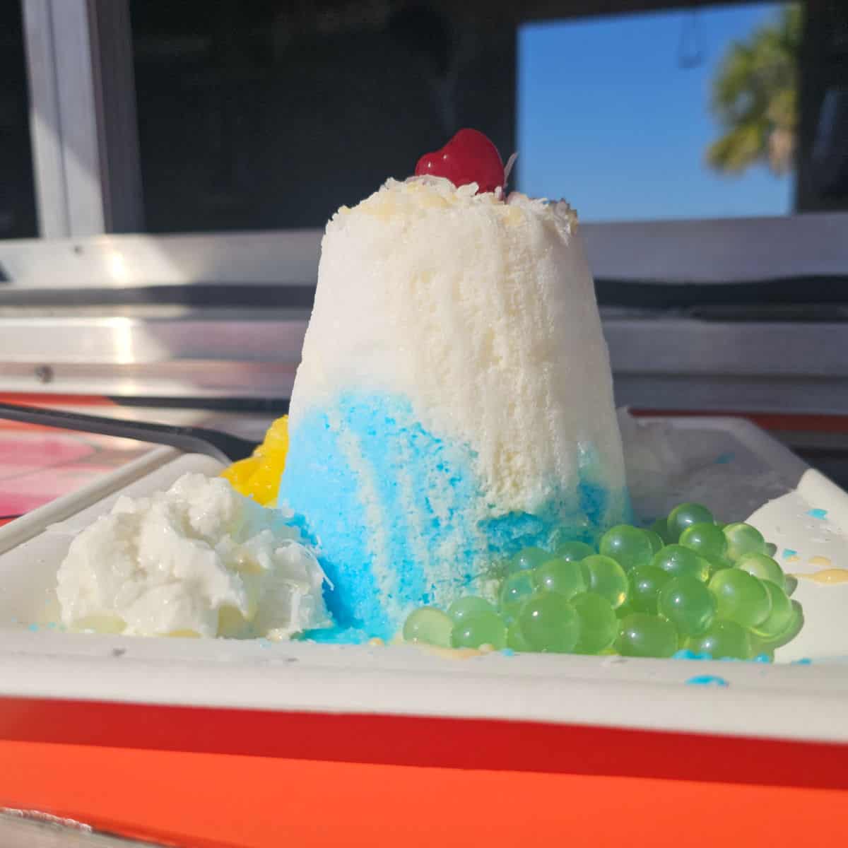 blue hawaiian snow with green boba and whipped cream on a white plate