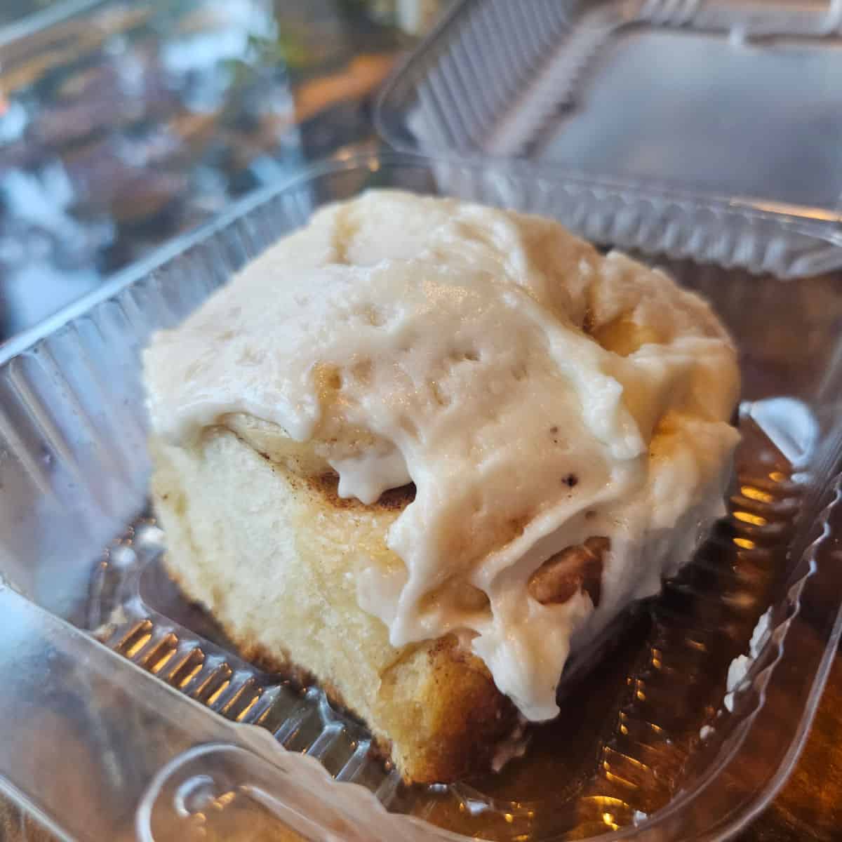cinnamon roll in a plastic container on a counter