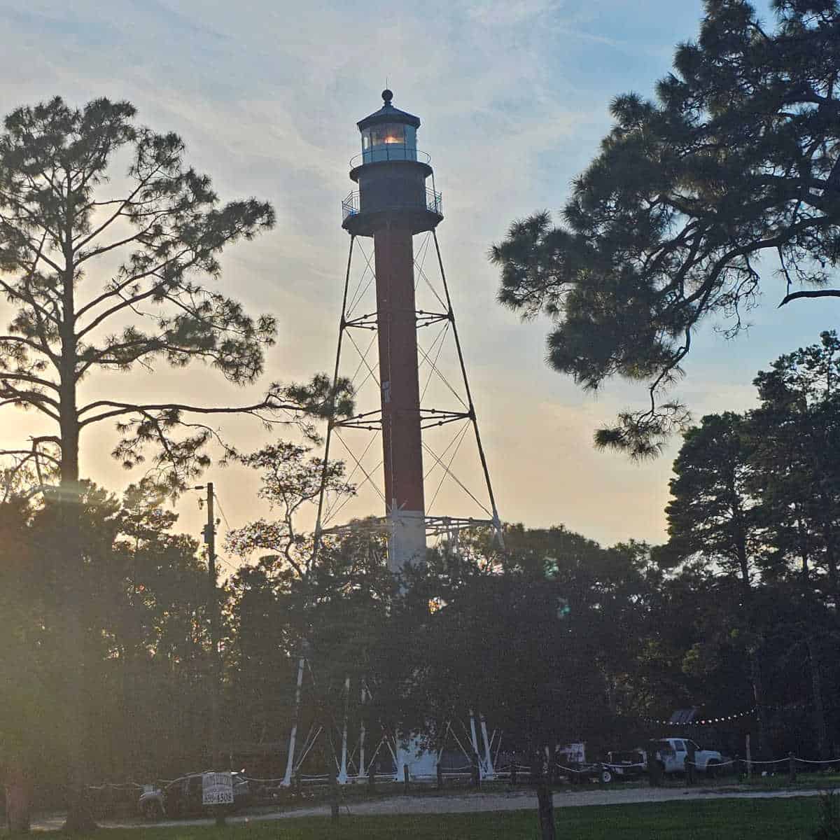 Crooked River Lighthouse with trees around it and a sunset sky
