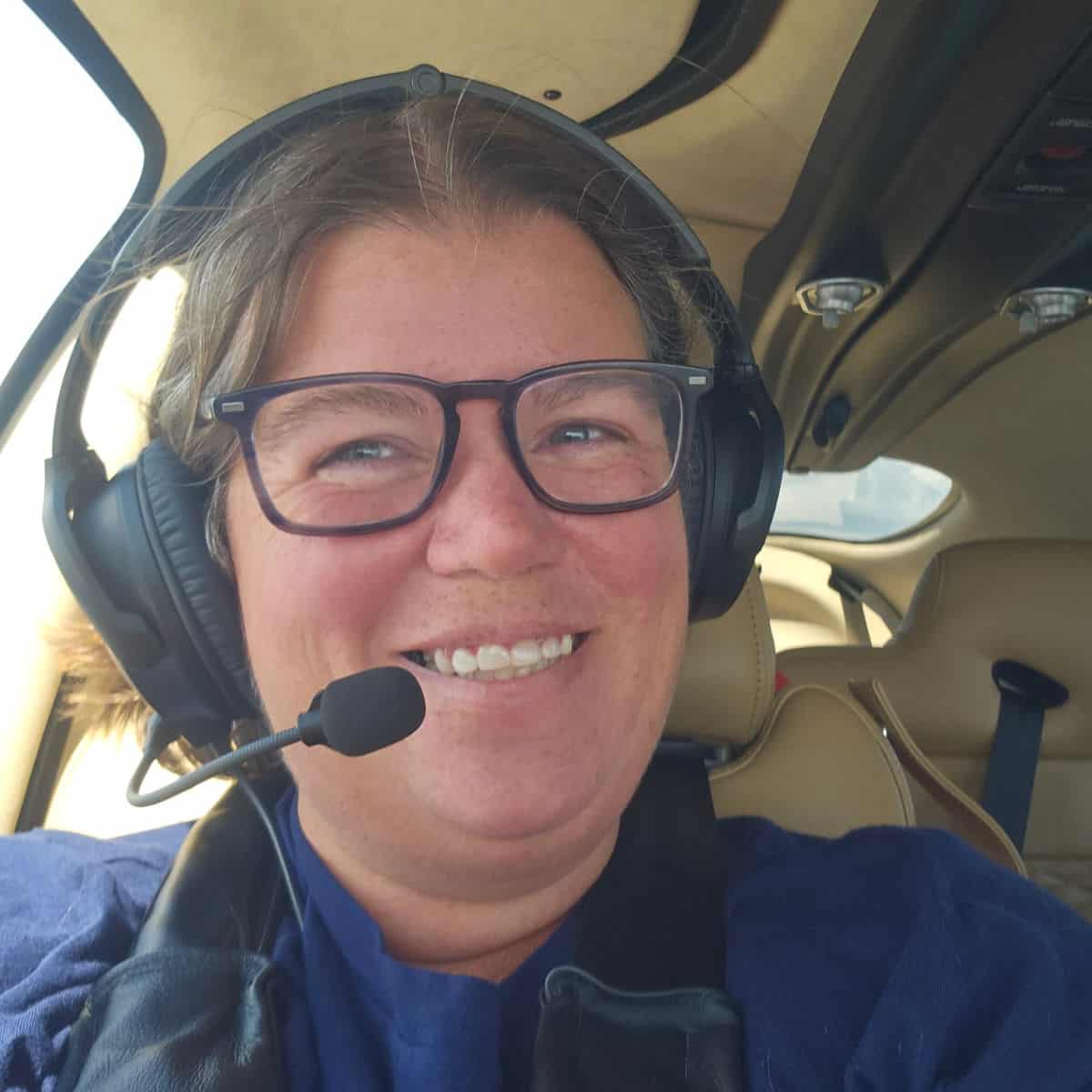 Tammilee smiling wearing headphones and a mic on an Elev8 plane