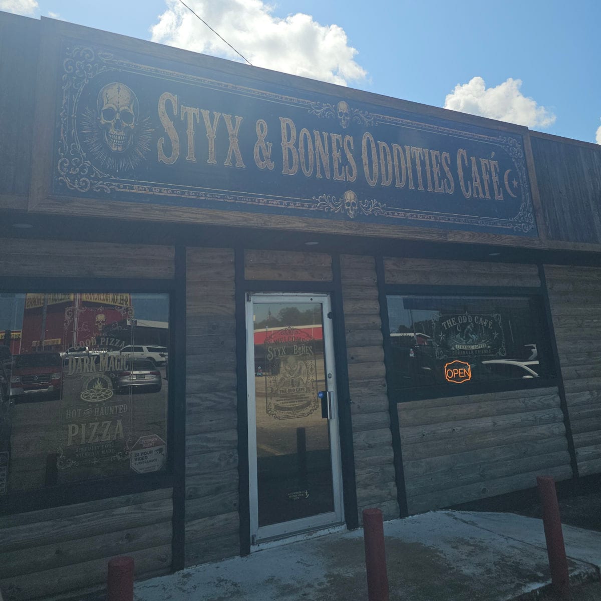 Styx & Bones Oddities Cafe sign on the exterior of a building with a glass entrance door