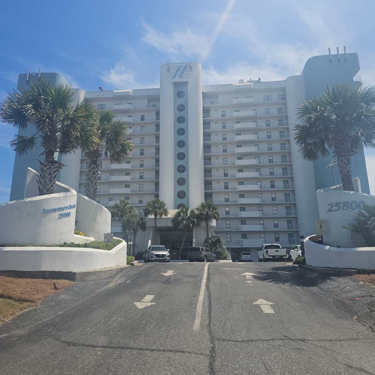 Summerchase Condo building with arrows leading up and down the driveway up to the parking area, tall building with circle windows down the center.