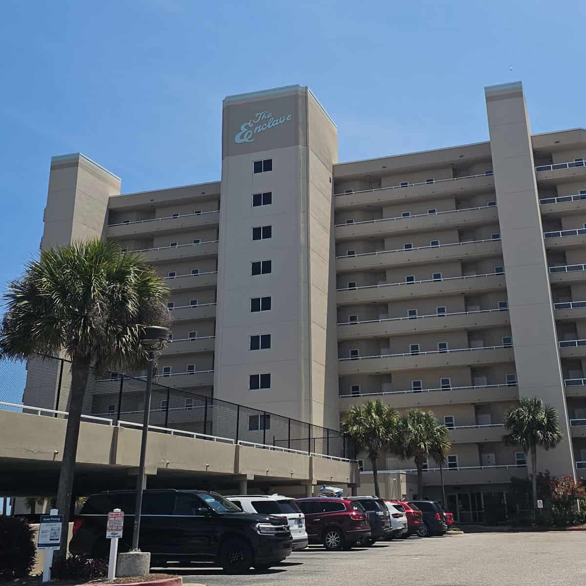 The Enclave on the top of a multi story condo building with cars parked in a row