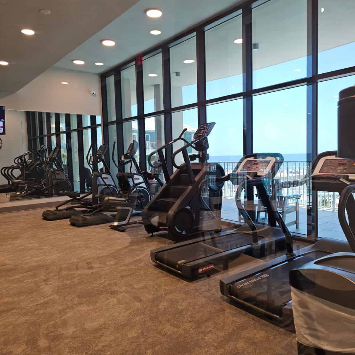 fitness center with ellipticals, treadmills, a stair climber facing towards the Gulf water