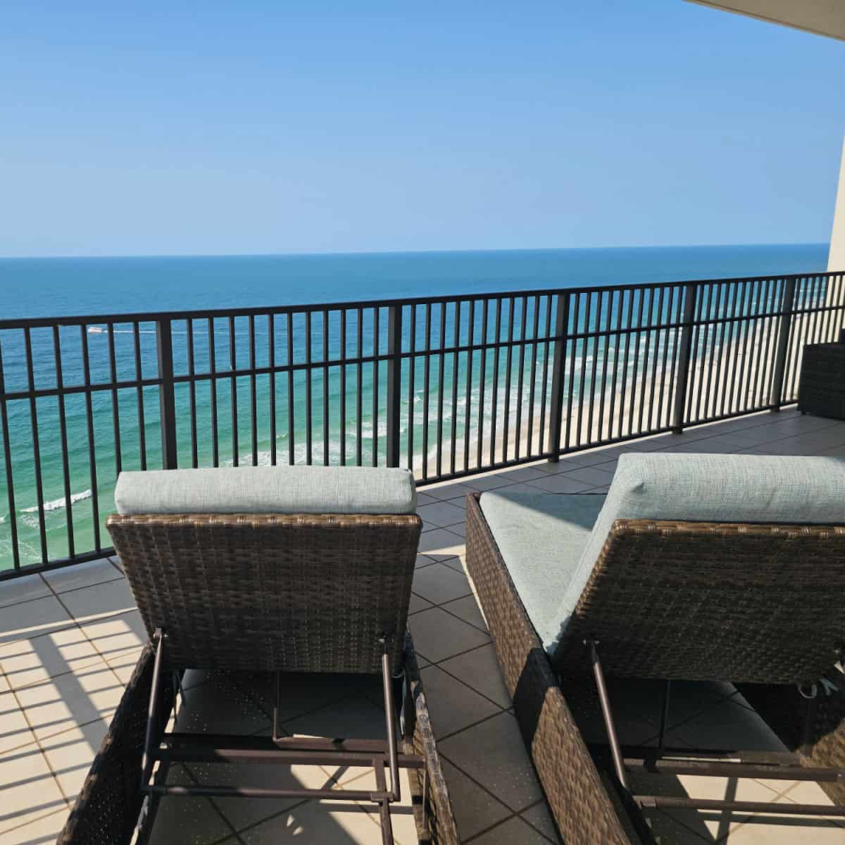 padded lounge chairs on a balcony looking out towards the Gulf waters