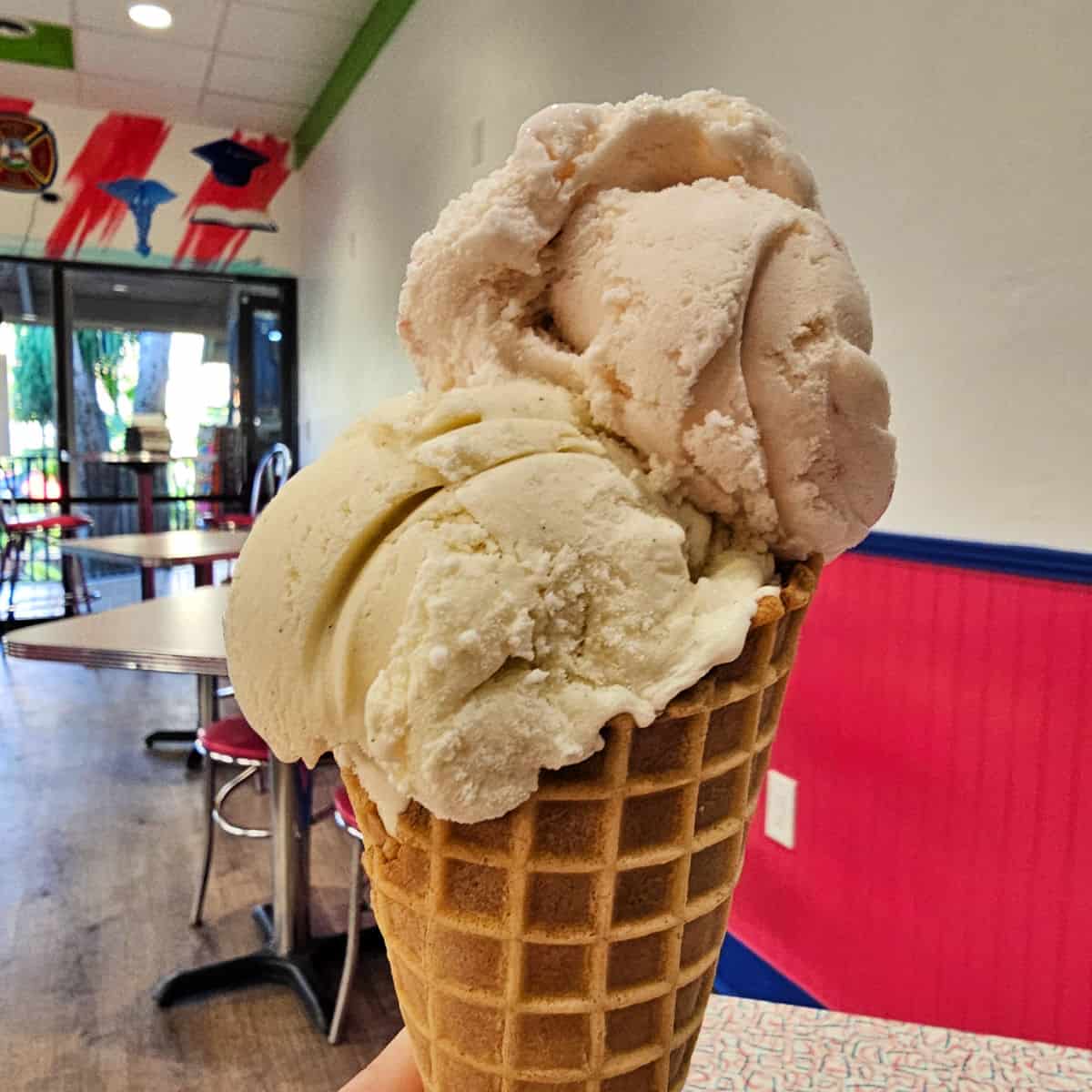 hand holding a waffle cone with two scoops