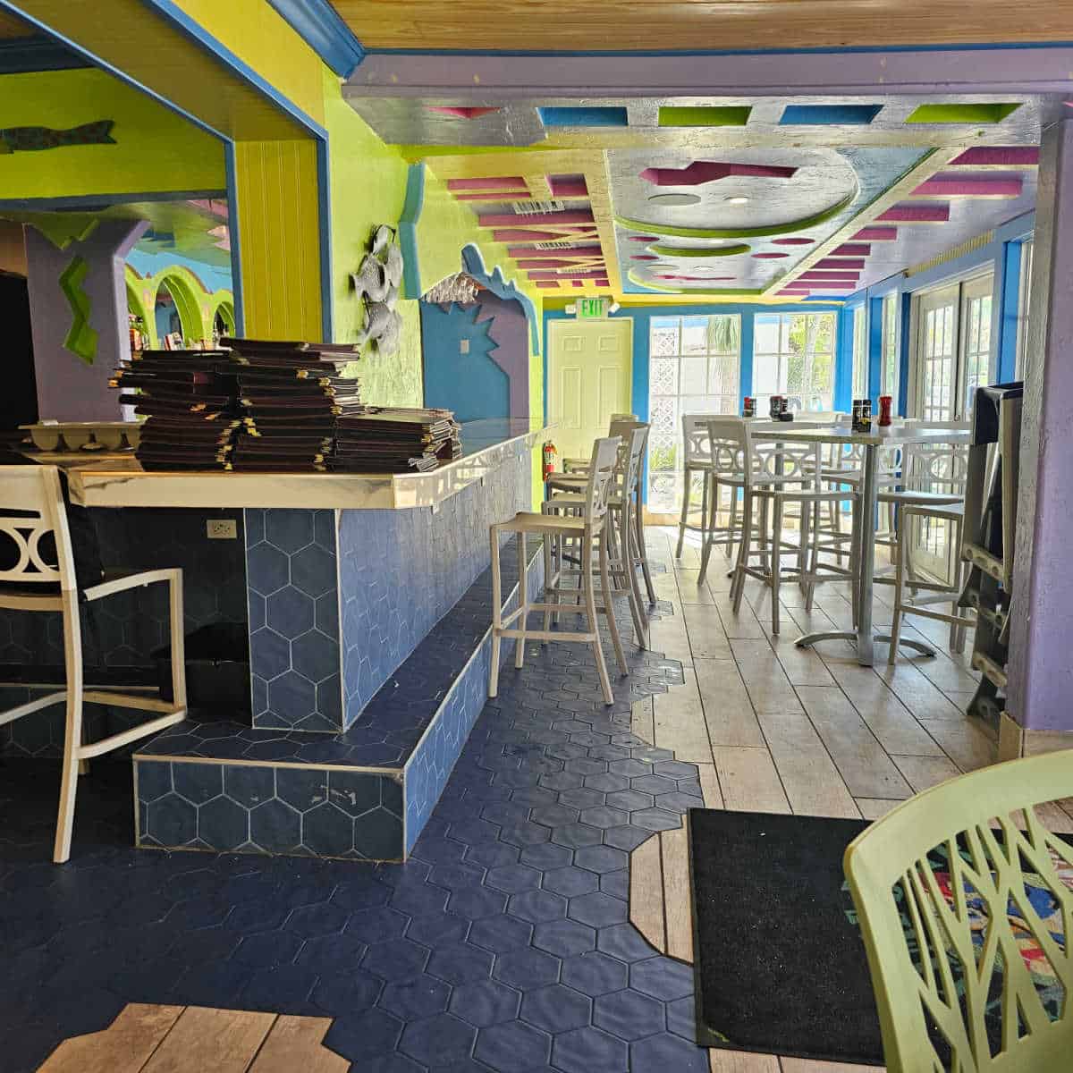 indoor bar area with tall table and chairs, vibrant color ceiling art and walls