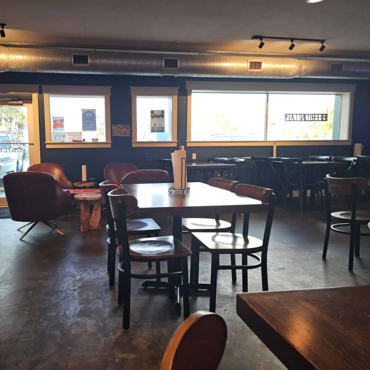 indoor restaurant seating with tables and chairs along with lounge chairs next to small wooden tables