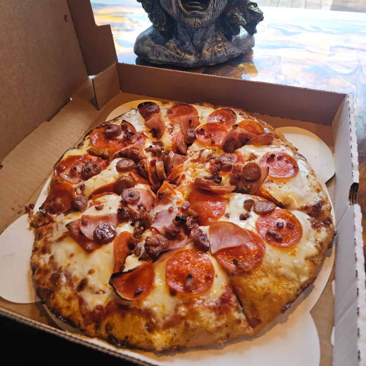 meat covered pizza in a pizza box on a counter