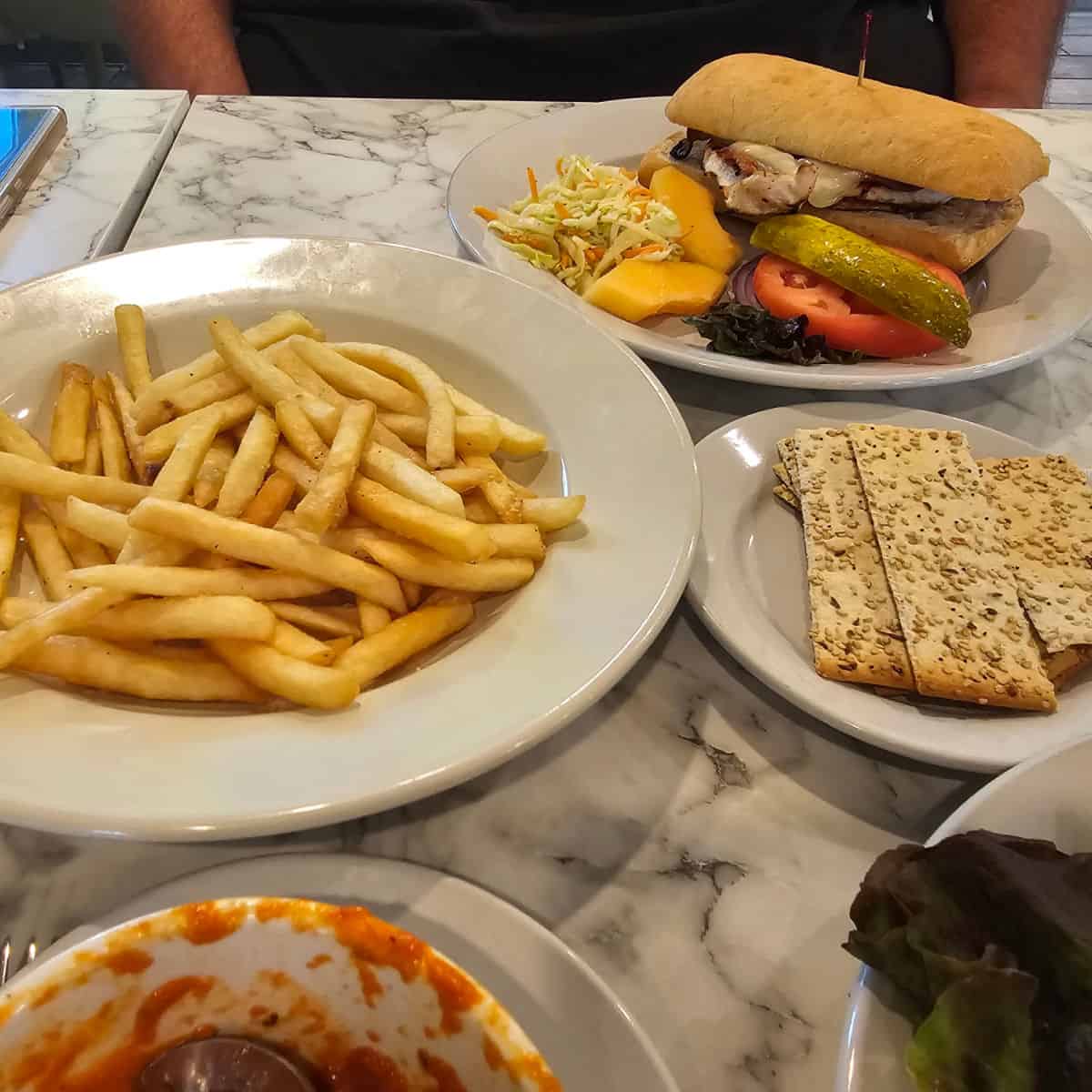 table with lunch plates including fries, crackers, soup, salad, and a sandwich
