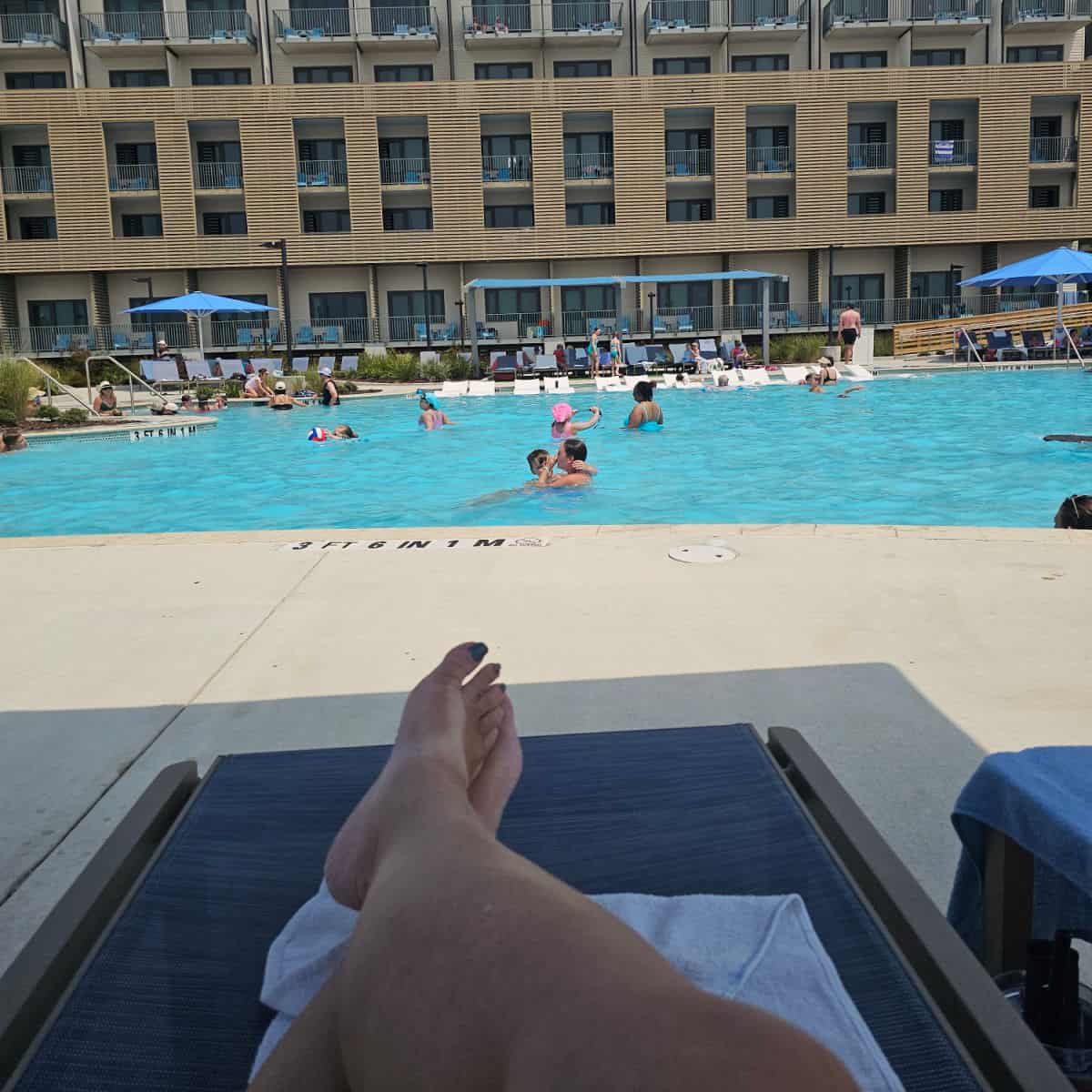 looking over legs on a blue lounge chair to the Lodge at Gulf State park pool
