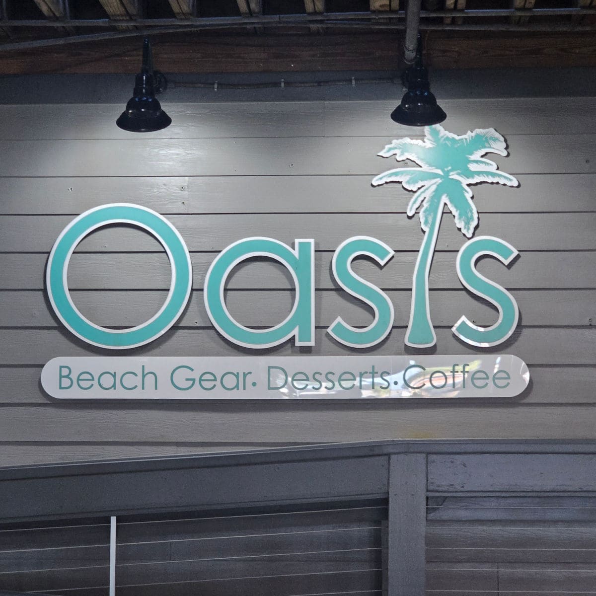 Oasis Beach Gear Desserts Coffee sign on the side of a grey building