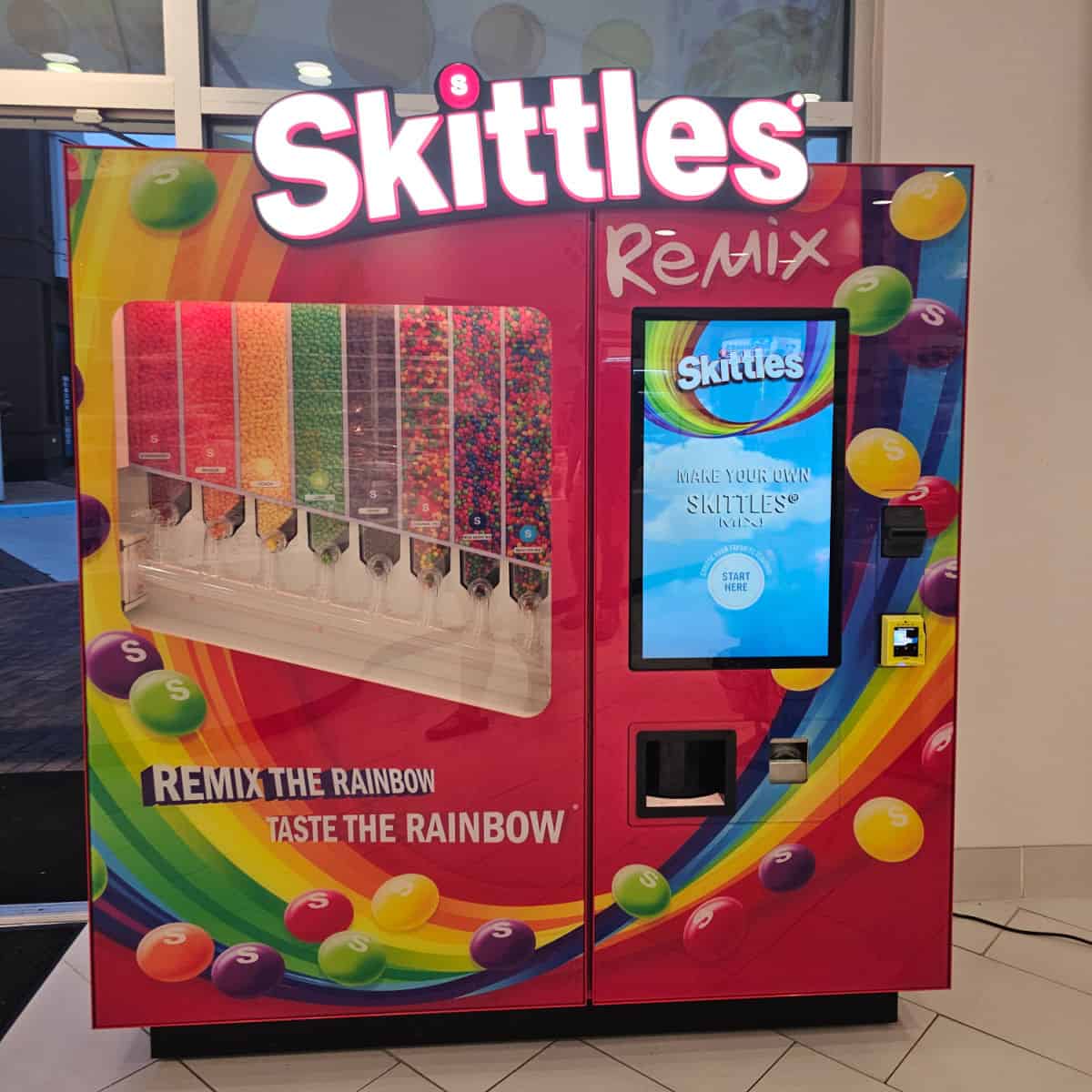 Skittles Remix machine with a rainbow of skittles divided by color and a touch screen