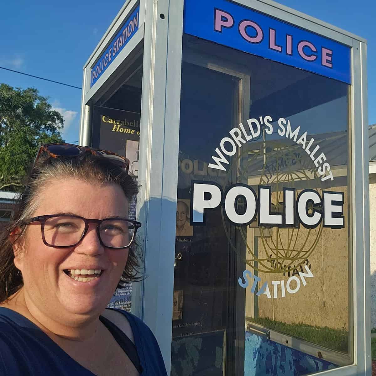 Tammilee standing next to the World's Smallest Police Station Carrabelle phone booth