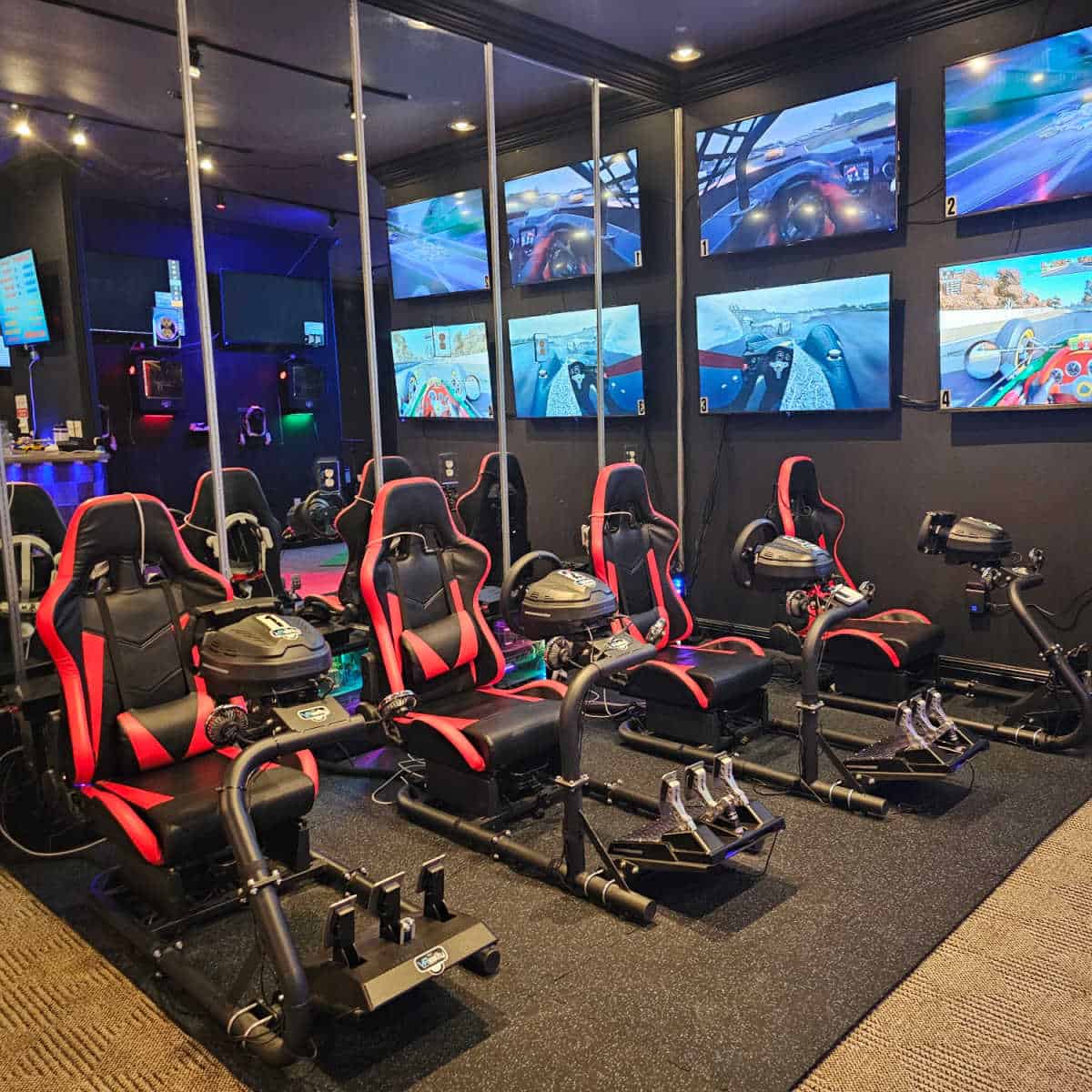 VR gaming chairs and steering wheels with TV screens on the wall