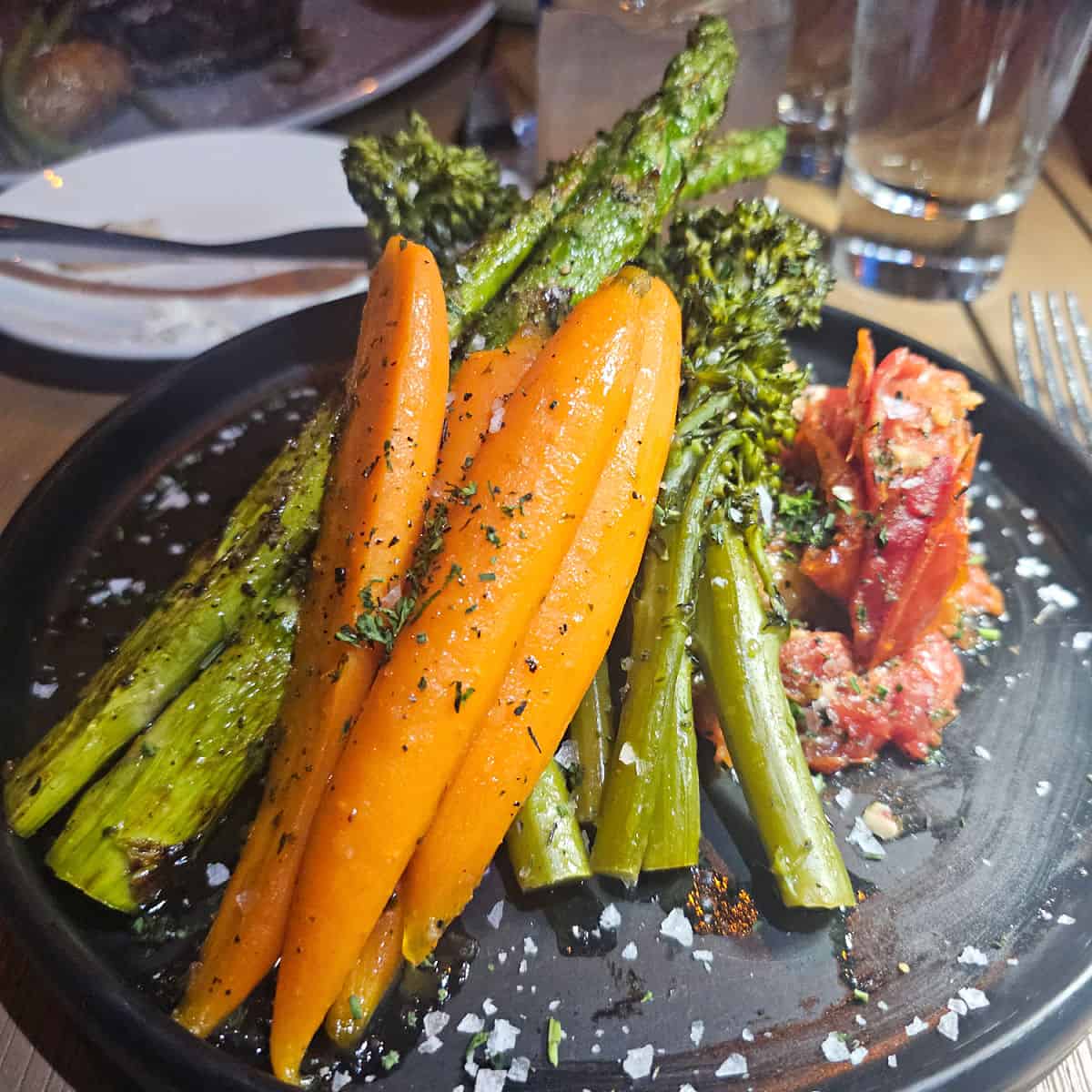 blue plate filled with carrots, asparagus, and other vegetables.