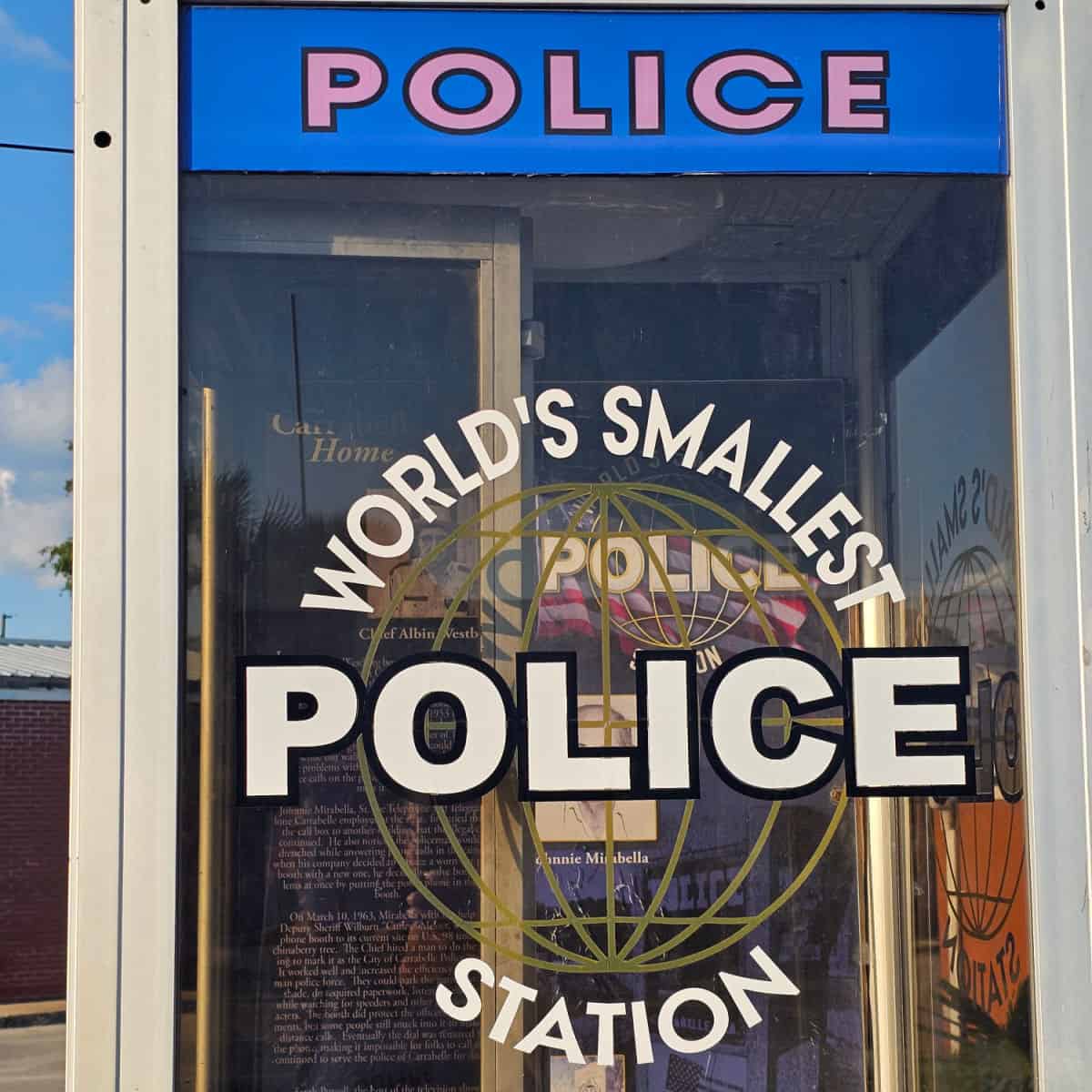 World's Smallest Police Station Carrabelle sign on the side of a phone booth