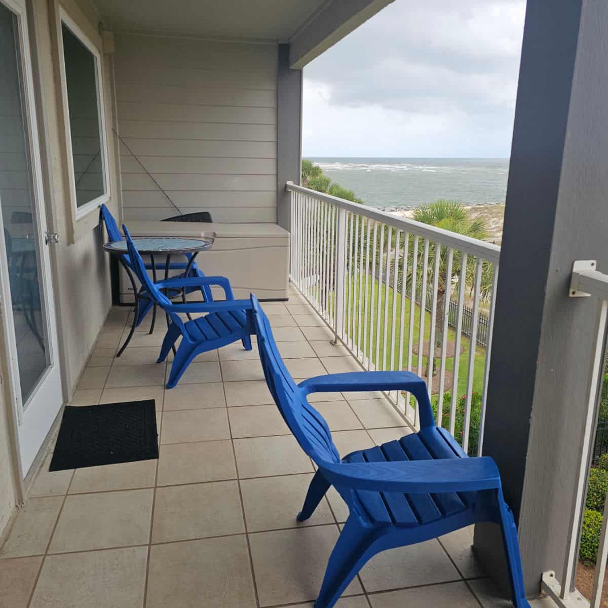 balcony looking out towards Perdido Pass with blue plastic Adirondack chairs and table