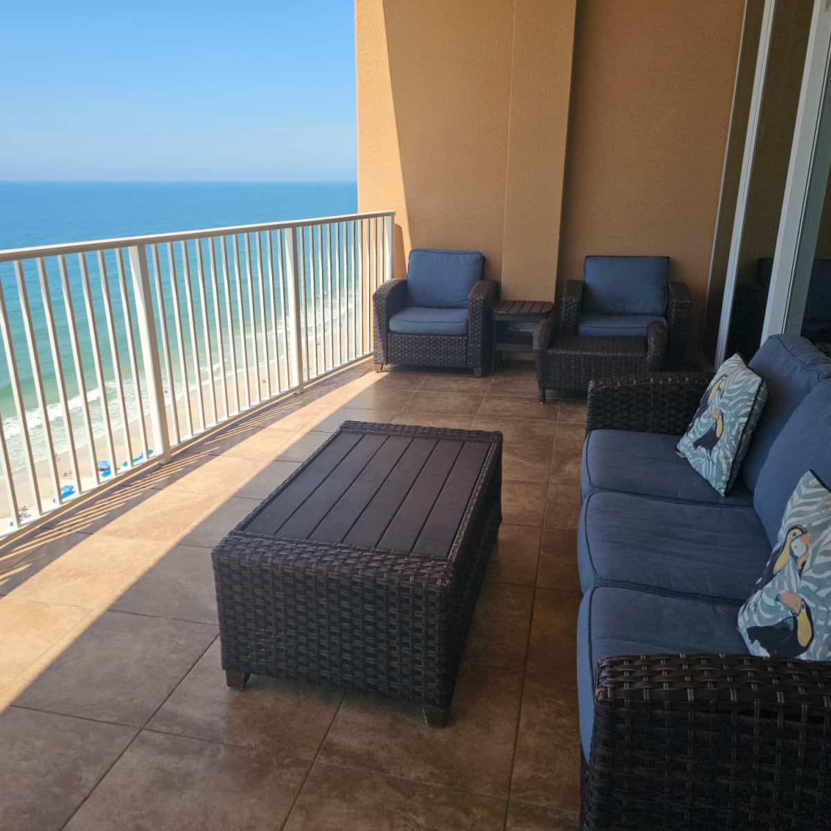 Balcony with couches and chairs with blue padded cushions, views out to the beach and Gulf of Mexico